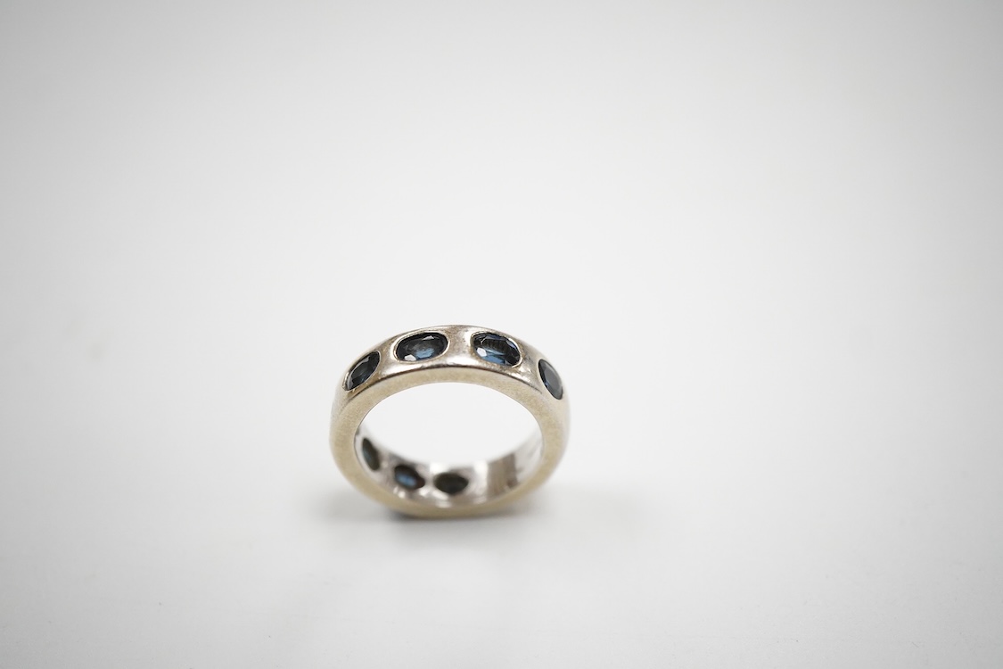 A recent Italian white metal (stamped 750) and seven stone gypsy set oval cut sapphire band, by Cristiano of Genoa, size N, gross weight 10.4 grams.